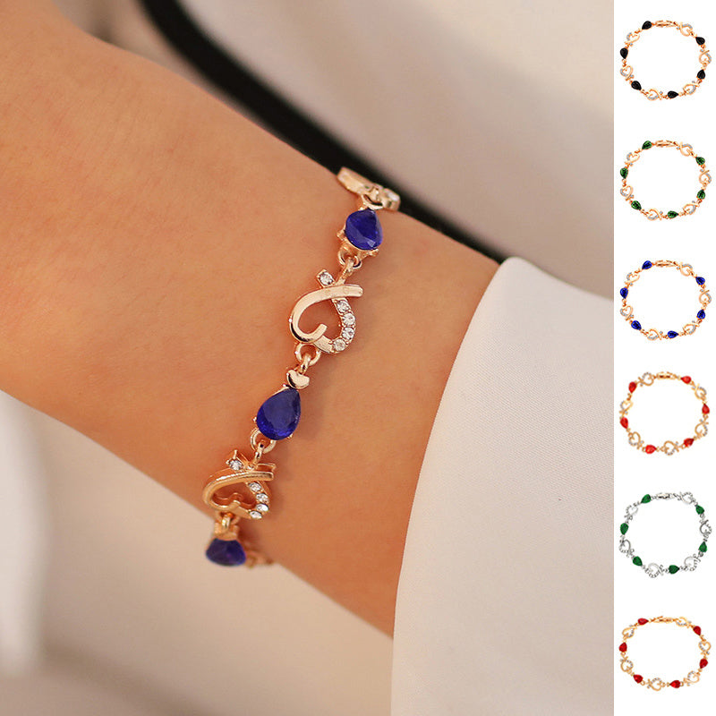 Heart-shaped rhinestone bracelet on wrist, available in multiple colors.