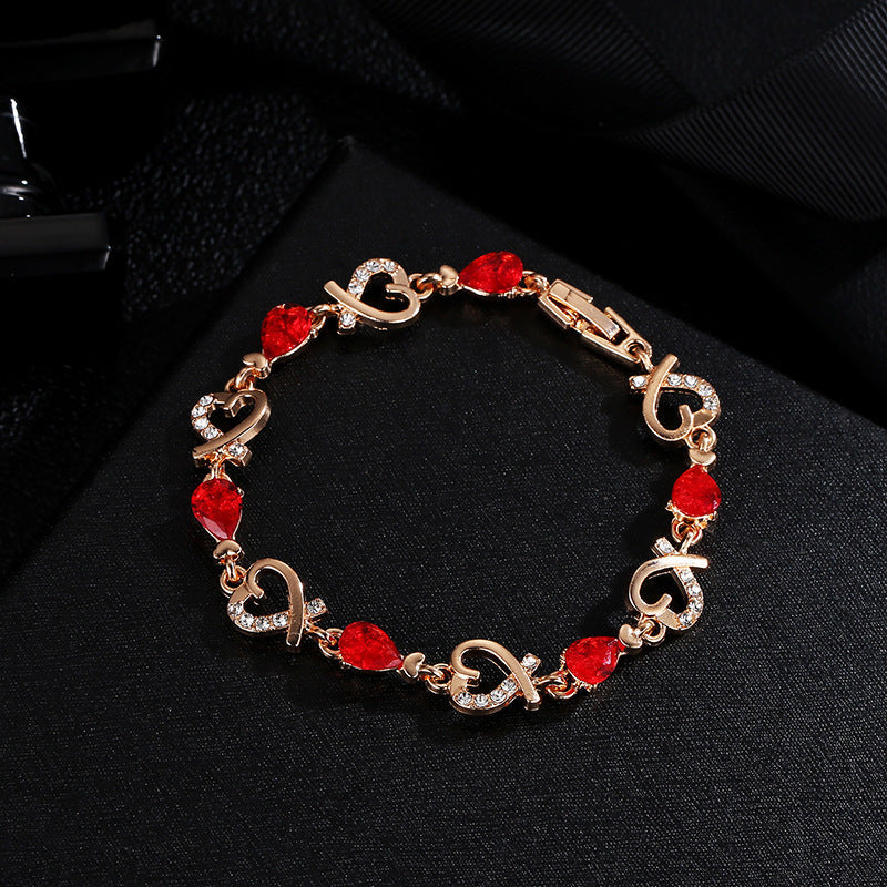 Heart-shaped bracelet with rhinestones, elegant copper design, red and clear stones, secure clasp.