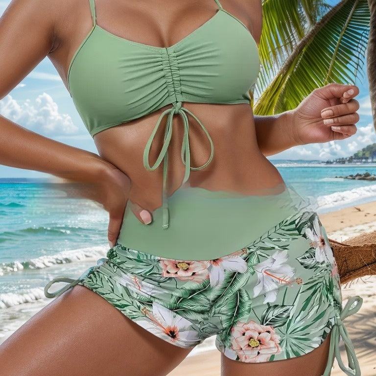 Women’s tropical print two-piece bikini with green shorts on the beach.