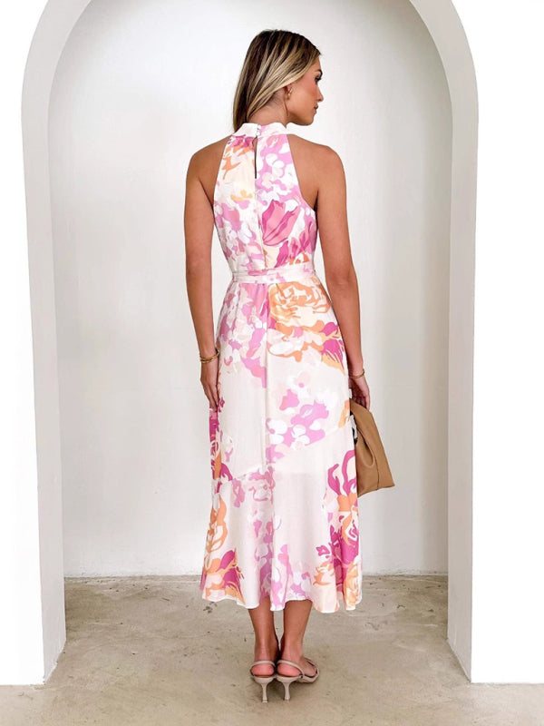 Sleeveless halter neck midi dress with pink and green floral pattern, asymmetric ruffled hem, and waist tie.