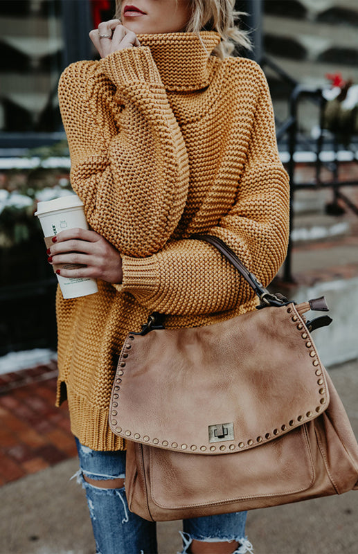 Women’s thick oversize turtle neck pullover sweater in mustard yellow with a leather handbag.