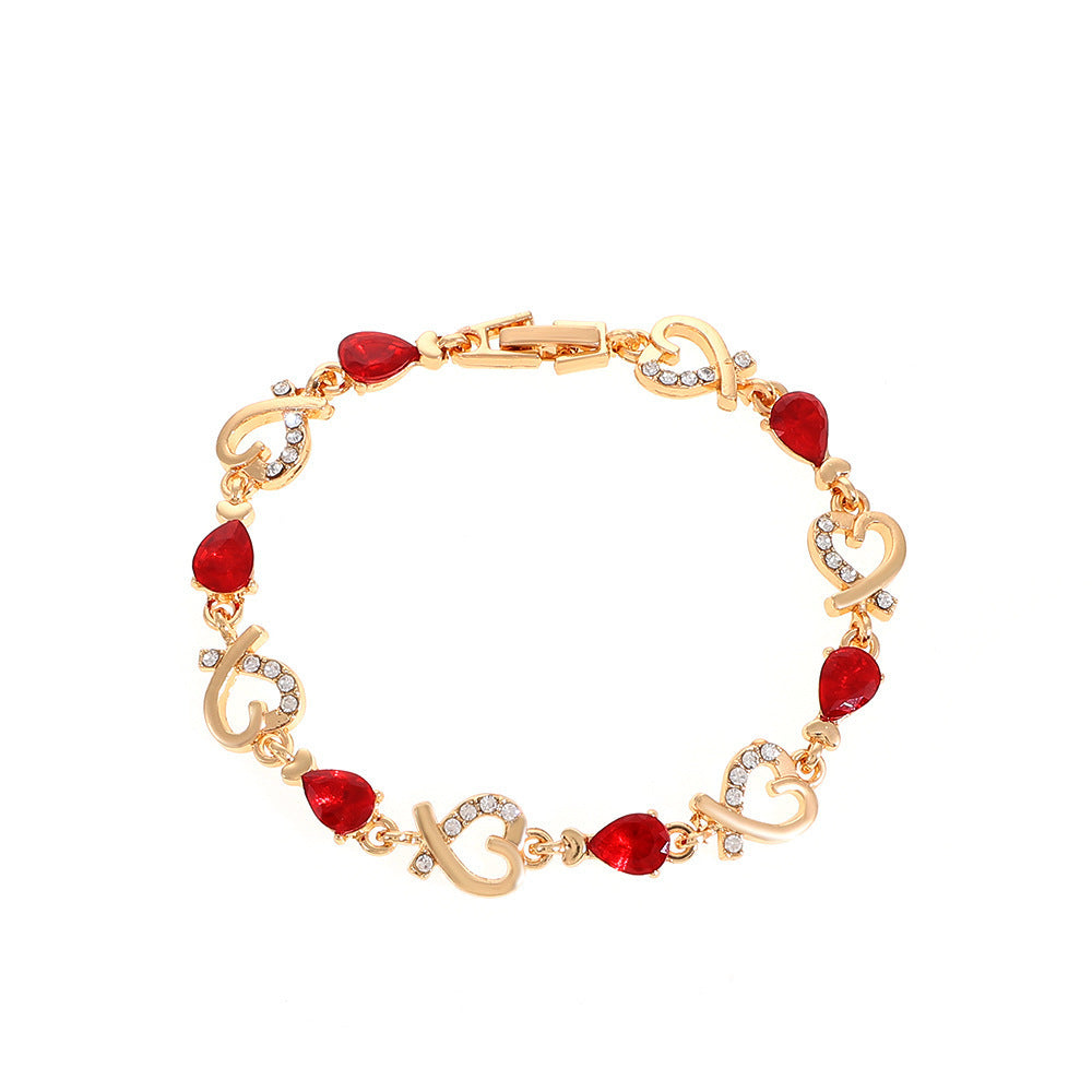 Heart-shaped bracelet with red rhinestones and gold clasp.