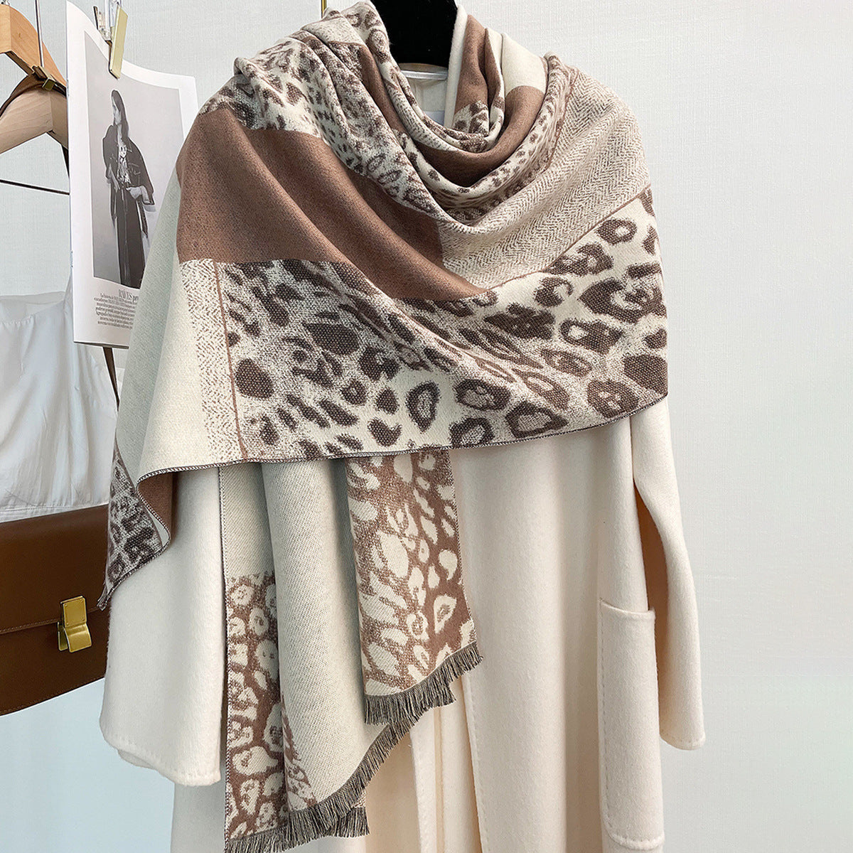 Leopard print shawl with color-blocking design hanging on a white coat.