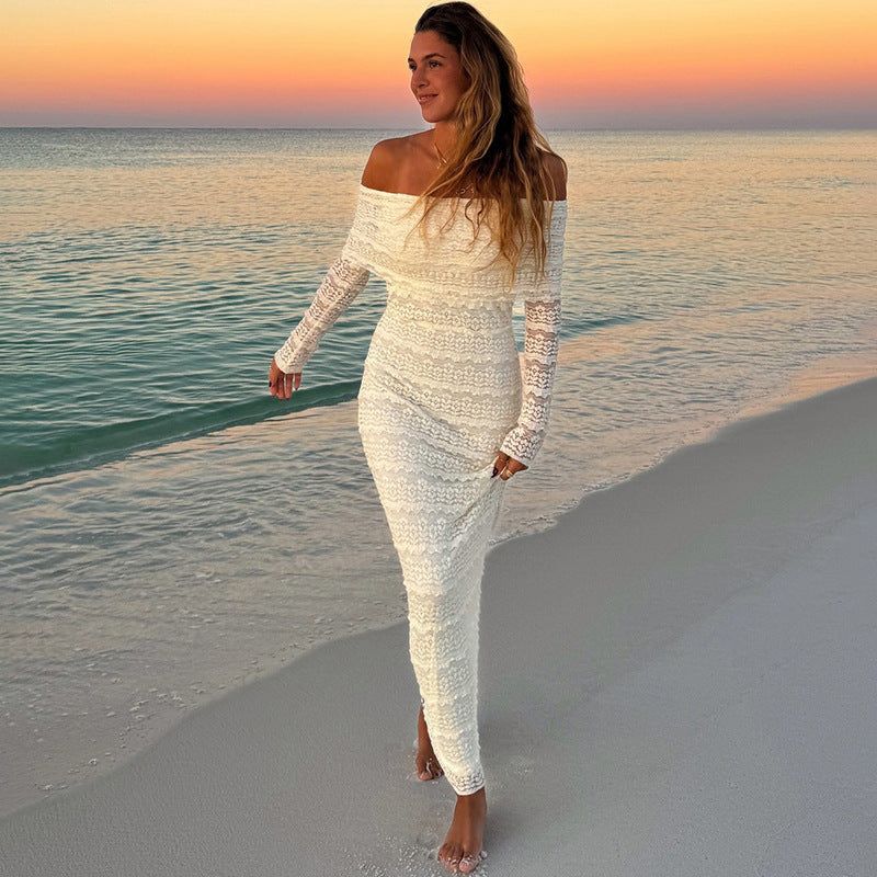 Elegant woman wearing an off-shoulder lace dress at sunset on the beach.