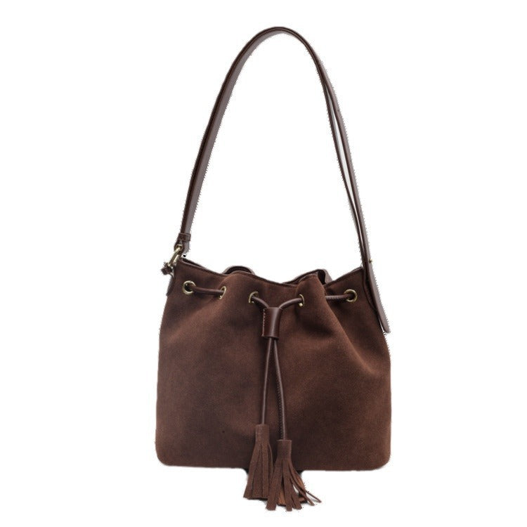 Bucket bag with tassel in brown PU leather and single strap.