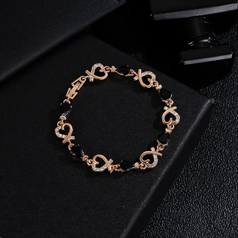 Heart-shaped bracelet with rhinestones on black background, elegant copper accessory.