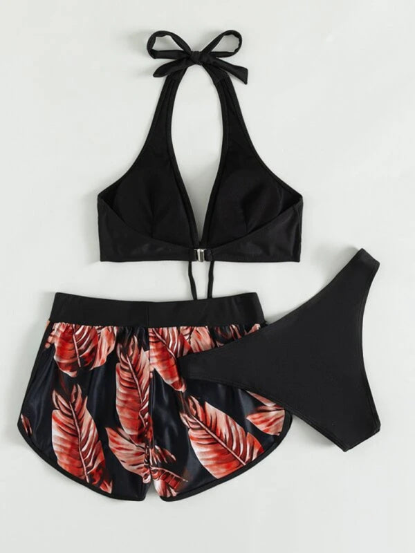 Women's tropical print halter neck bikini three-piece set with top, bottoms, and printed swim shorts.