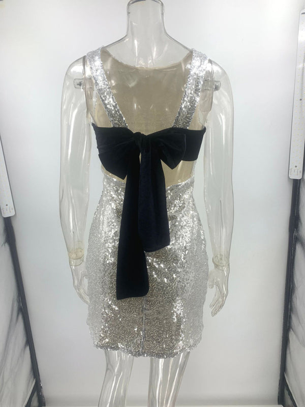 Backless silver sequin dress with black bow, sleeveless mini style.