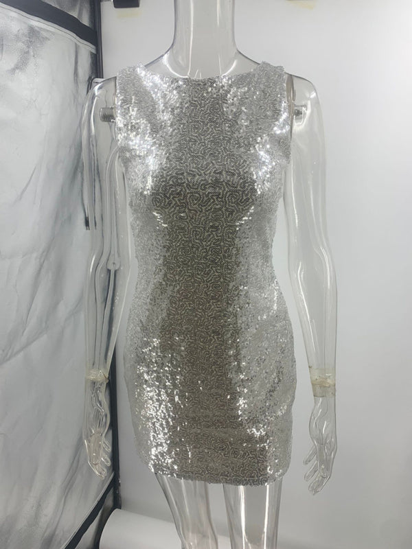 Backless silver sequin dress with sleeveless design and bow detail.